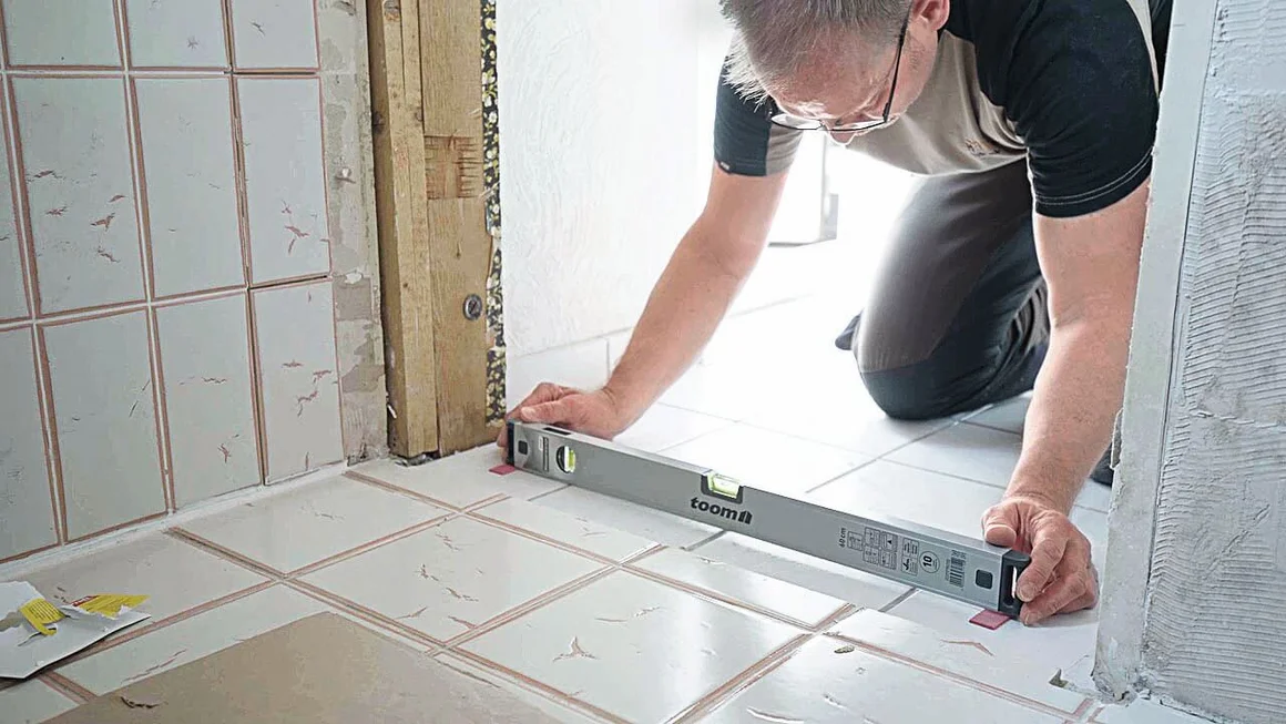 Person prüft Fliesen mit Wasserwaage